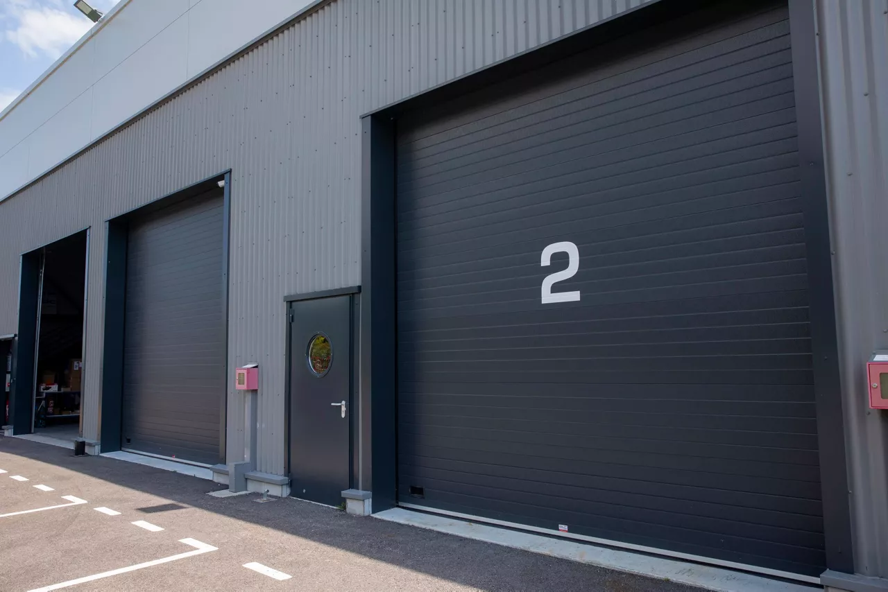 Portes sectionnelles industrielles anthracite sur un bâtiment d'entreprise