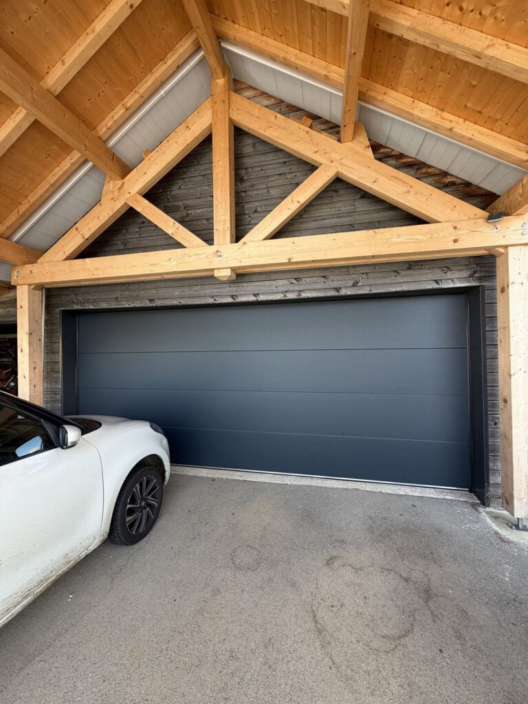 Porte de garage anthracite sous un carport en bois